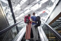 Vista posteriore della coppia sulla scala mobile in aeroporto — Foto stock