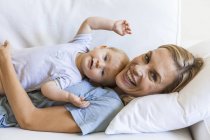 Happy mother cuddling with her baby girl on couch — Stock Photo