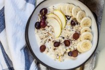 Muesli bowl with bananas, apples, grapes, with coffee — Stock Photo