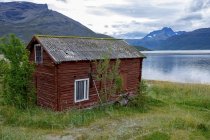 Norwegen, Skibotn, Holzhütte am See in den Bergen — Stockfoto