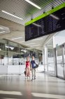 Casal feliz andando no aeroporto com mulher acenando — Fotografia de Stock