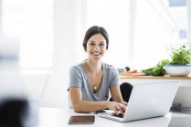 Happy woman sitting at desk, working from home, using laptop — Stock Photo