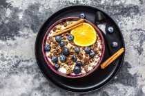 Crunchy muesli with blueberries, slice of orange and cinnamon sticks — Stock Photo