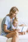 Madre e bambina seduta sul divano e guardando il libro di foto — Foto stock