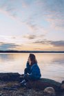 Giovane donna seduta al lago Inari, guardando la vista, Finlandia — Foto stock