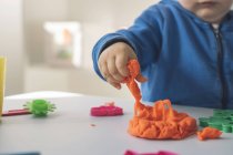 Hand of baby girl taking modeling clay, close-up — Stock Photo