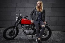 Fiduciosa giovane donna con moto guardando altrove — Foto stock