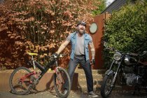 Homme barbu caucasien hurlant dans le casque de vélo à l'extérieur avec vélo et moto — Photo de stock