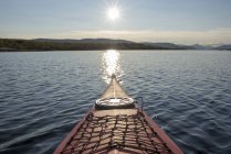 Finland, Lappland, Kilpisjaervi, canoe on lake against the sun — Stock Photo