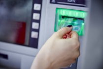 Primer plano de la mujer que pone la tarjeta en la ranura del cajero automático - foto de stock