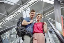 Happy couple on escalator at the airport — Stock Photo
