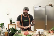 Вегетарианец режет яблоки на кухне и смотрит в камеру — стоковое фото