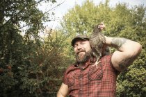 Man in his own garden, man with free range chicken on his shoulder — Stock Photo