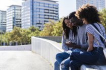 Tre amici trascorrono del tempo in città, utilizzando lo smartphone — Foto stock
