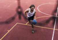 Молодой человек играет в баскетбол на баскетбольной площадке — стоковое фото