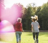 Внучка и бабушка веселятся, бегают вместе в парке — стоковое фото