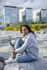 Young woman sitting on rocks at the beach, relaxing — Stock Photo