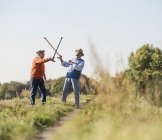 Due vecchi amici scherma nei campi con i loro bastoni da passeggio — Foto stock