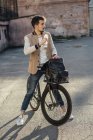 Молодой человек с пригородным велосипедом отдыхает на заднем дворе в городе — стоковое фото