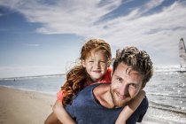 Países Bajos, Zandvoort, retrato del padre sonriente llevando a su hija en la playa — Stock Photo