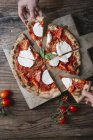 Comer una pizza con mozzarella, tomar una rebanada de pizza a mano — Stock Photo