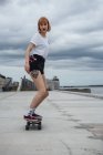 Молодая женщина катается на скейтборде у реки — стоковое фото