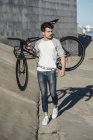 Молодий чоловік проведення приміського велосипеда fixie на бетонній стіні — стокове фото