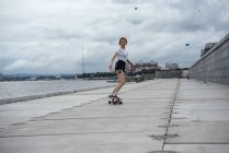 Jeune femme chevauchant sculpteur skateboard au bord de la rivière — Photo de stock
