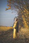Посмішка вагітна жінка стоїть на лісовій стежці поруч спаржі восени. — стокове фото