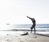 Francia, Bretagna, giovane uomo che fa un manubrio sulla spiaggia vicino alla tavola da surf — Foto stock