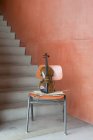 Violin, bow and sheet music on wooden chair at staircase — Stock Photo