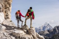 Italy, Cortina d 'Ampezzo, couple with rope and climbing equipment holding hands and looking at view — стоковое фото