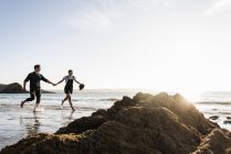 Francia, Bretagna, felice giovane coppia che corre mano nella mano sulla spiaggia — Foto stock