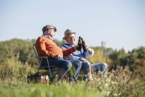 Dos viejos amigos sentados en el campo, bebiendo cerveza, hablando de los viejos tiempos - foto de stock
