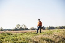 Senior man carrying traveling bag, walking in the fields — Stock Photo