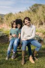 Família feliz sentada em um banco em um jardim — Fotografia de Stock
