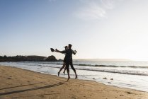 Francia, Bretagna, felice giovane coppia che salta sulla spiaggia al tramonto — Foto stock