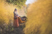 Вагітна жінка восени сидить на кріслі в полі спаржі. — стокове фото
