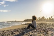 Donna seduta sulla spiaggia al tramonto — Foto stock