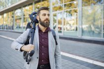 Businessman carrying scooter on street — Stock Photo
