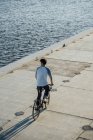 Junger Mann mit Fahrrad auf Uferpromenade am Ufer — Stockfoto