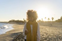 Жінка з жовтим шарфом, користуючись смартфоном на пляжі. — стокове фото