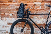 Backpack in cargo cage of acustomised commuter fixie bike at brick wall — Stock Photo