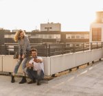Giovane coppia rilassante sulla terrazza sul tetto al tramonto scattare selfie con il telefono cellulare — Foto stock