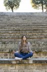 Giovane donna seduta all'aperto sulle scale facendo yoga — Foto stock