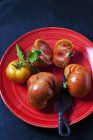 Tomates entières et tranchées de boeuf 'Chocolate Stripes' sur plaque rouge — Photo de stock