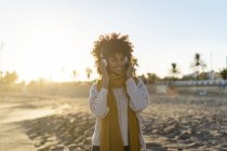 Frau mit gelbem Schal hört Musik am Strand — Stockfoto