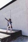 Junge Frau gestikuliert vor einer Mauer — Stockfoto