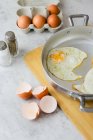 Eggs in a box, fried eggs in pan and eggshells — Stock Photo