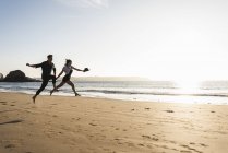 France, Brittany, happy young couple jumping on the beach at sunset — Stock Photo